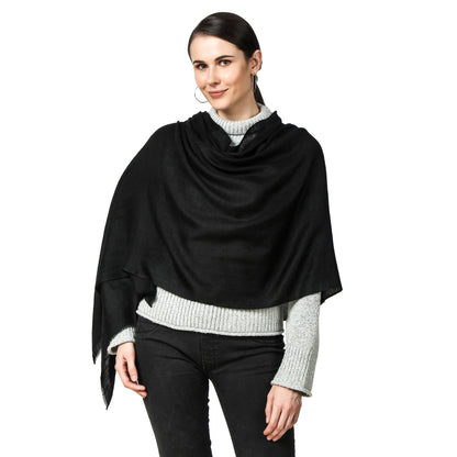 A woman wearing a Black Cashmere Scarf wrapping it around herself